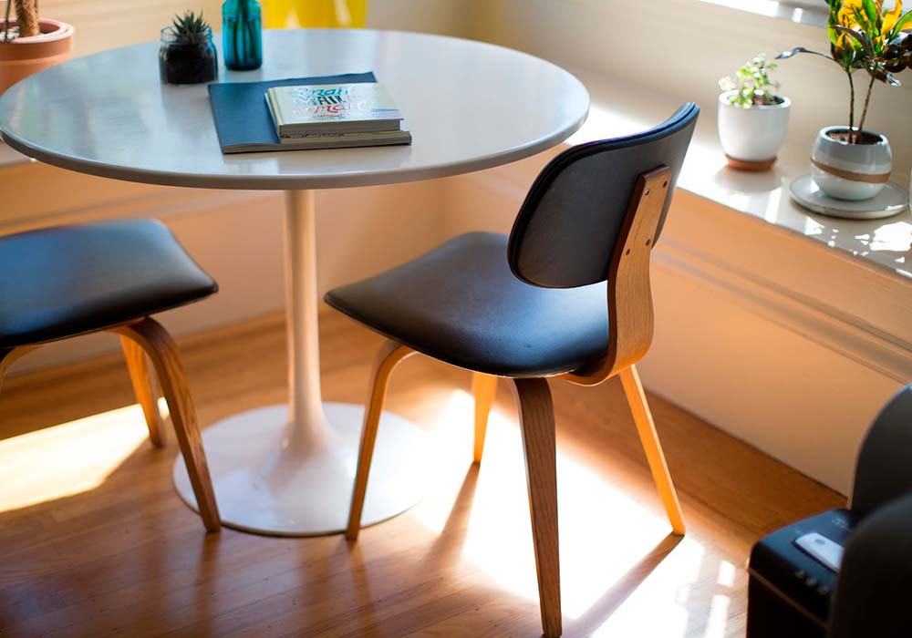 comedor con mesa de vidrio y sillas de madera con asiento color negro