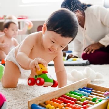 Bebe asiatico jugando con un carro